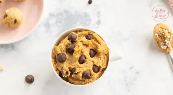 Leckeres Protein Cookie Dough Rezept in einer Tasse, mit Schokostückchen und auf einem Löffel mit Streuseln.