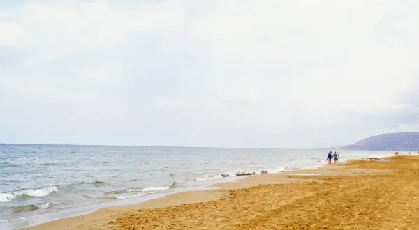 Spokojne morze i piaszczysta plaża na Zakynthos w maju. Kilka osób spaceruje brzegiem, ciesząc się łagodnym słońcem i ciszą.