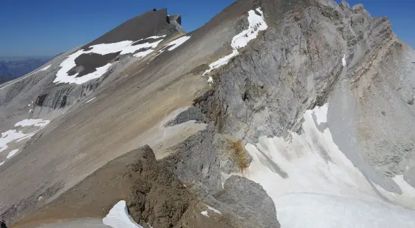 Vue spectaculaire d'une crête rocheuse et enneigée lors d'une barrhorn randonnée. Le ciel bleu azur domine.