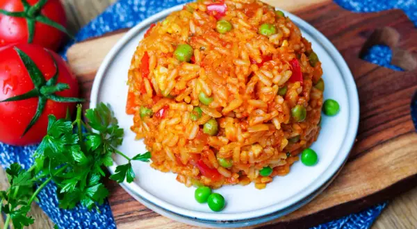 Ein Berg aus aromatischem Djuvec Reis mit Erbsen und Paprika, garniert mit frischer Petersilie und Tomaten.