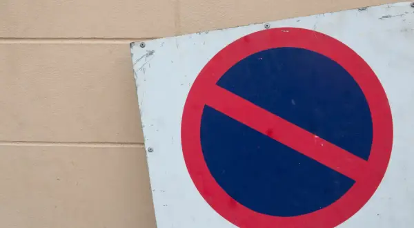Znak zakazu zatrzymywania się, b35 znak, na tle beżowej ściany.