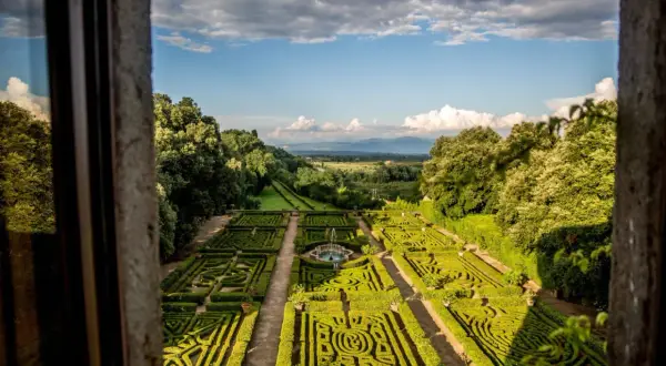 Giardini all'italiana del Castello Ruspoli, con siepi geometriche, fontana centrale e vista panoramica sulla campagna.
