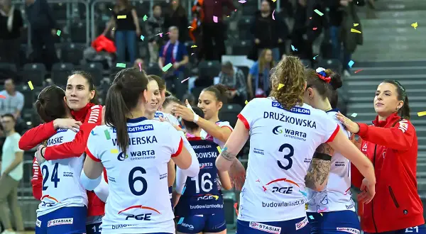 Siatkarki w strojach sportowych przytulają się, obsypane konfetti.