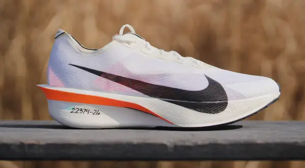 Białe buty treningowo startowe Nike z czarnym logo. Pomarańczowe akcenty i numeracja na podeszwie.