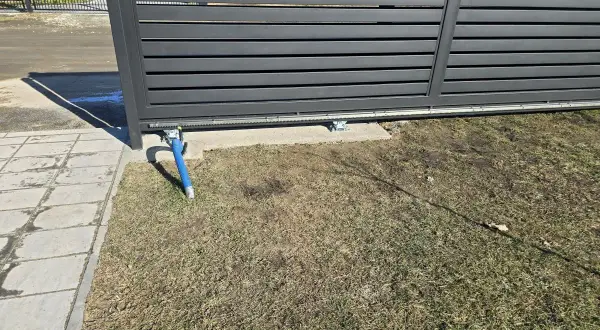 Widoczny mechanizm bramy przesuwnej, z wózkami podtrzymującymi. Jaki rozstaw wózków do bramy przesuwnej jest kluczowy dla płynnego działania.
