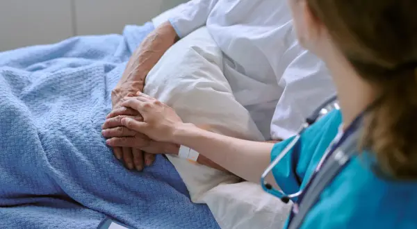 Dłoń pielęgniarki na dłoni pacjenta, symbol wsparcia w leczeniu. Terapia celowana daje nadzieję.