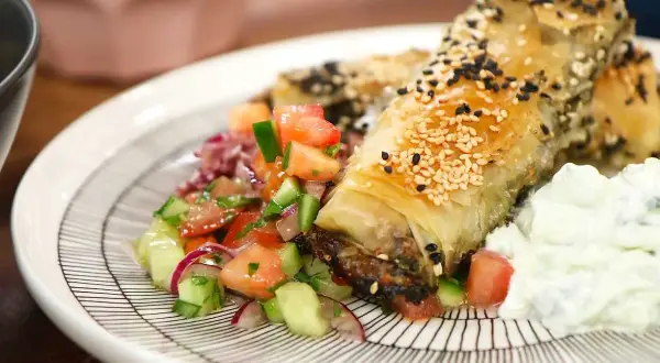 Krispiga filodegsrullar med sesamfrön, serverade med en fräsch tomatsallad och yoghurt. Ett utsökt burek recept!
