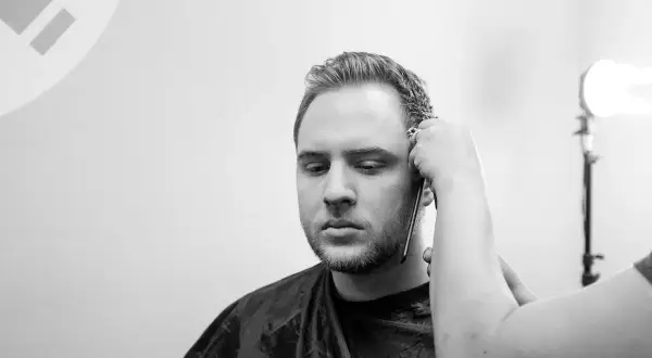 Un uomo con barba e basette viene tagliato. Diverse tipi di basette sono possibili, ma queste sono in fase di definizione.