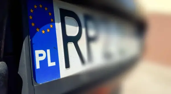 Zbliżenie na polską tablicę rejestracyjną z symbolem UE. To ważny moment, pierwsza rejestracja samochodu.