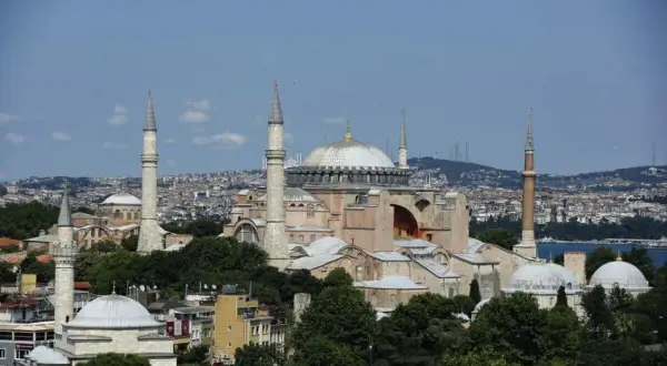 Hagia Sofia i Istanbul, en ikonisk byggnad med kupoler och minareter, reser sig mot en blå himmel.