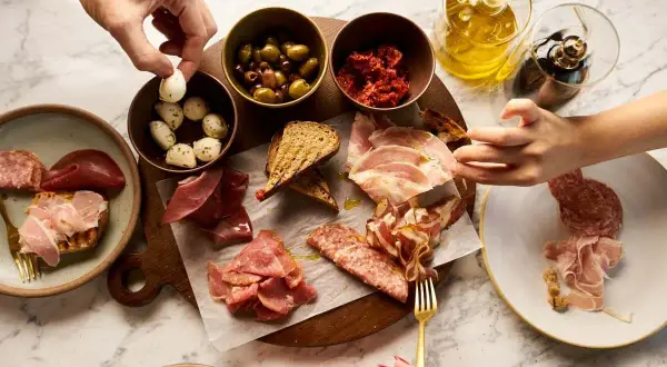 En härlig italiensk charkbricka med oliver, soltorkade tomater, mozzarella, bröd och olika sorters charkuterier.