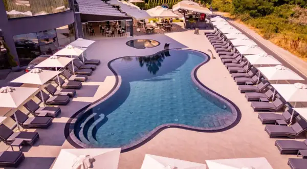 Relaks przy basenie w Laki Hotel & Spa. Leżaki i parasole czekają na gości.