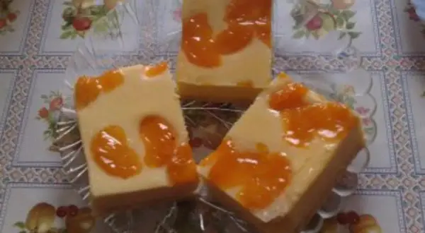 Drei Stücke faule weiber kuchen mit Mandarinen auf einem Tisch mit Blumenmuster.