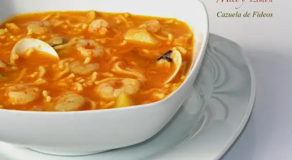 Cazuela de fideos con gambas y mejillones en un cuenco blanco.