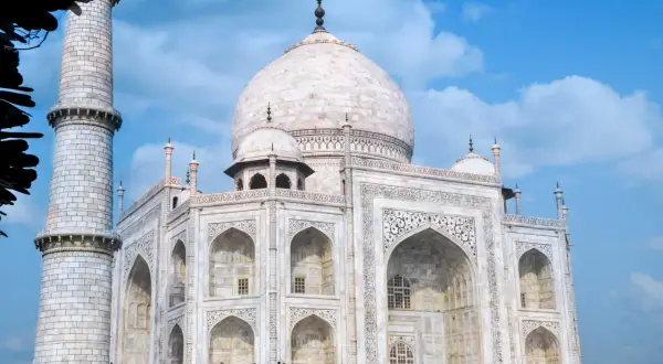 Biały marmur Taj Mahal, jeden z najpiękniejszych zabytków w Indiach, lśni na tle błękitnego nieba.