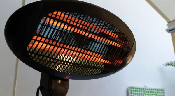 Lampada infrarossi terapia con elementi riscaldanti incandescenti arancioni dietro una griglia nera.