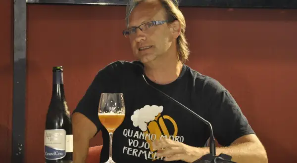 Uomo con bicchiere e bottiglia di birra artigianale, con maglietta che recita "Quando moro vojo fermentare". Non è birra industriale, ma passione!