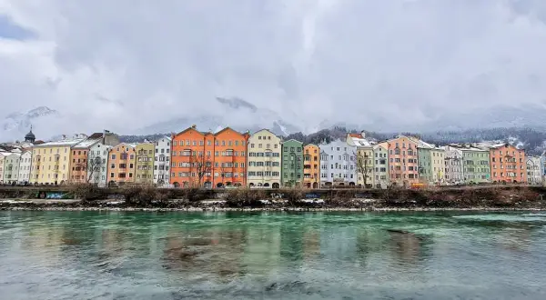 Kolorowe kamienice nad rzeką Inn, w tle ośnieżone góry. Idealne miejsce, by zobaczyć Innsbruck.