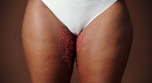 Féminité et saignement grossesse. Des paillettes rouges sur la peau, évoquant la fragilité et la vie.