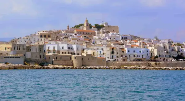 Un borgo bianco a picco sul mare, con un campanile in cima. Ricorda il vino primitivo, significato di sole e terra pugliese.