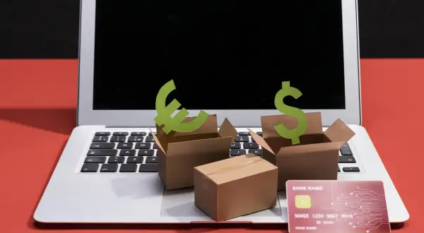 Ideas para como hacer una tienda virtual: cajas, símbolos de euro y dólar, tarjeta de crédito y laptop.