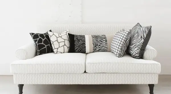 Un divano bianco con cuscini a fantasia animalier e pois: un'idea su come disporre i cuscini sul divano per un tocco moderno.