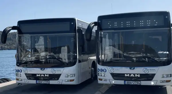 Två vita bussar står redo vid Skiathos flygplats för att transportera resenärer.