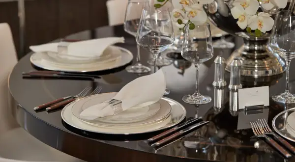 Elegant dukning med bestick, en vit servett med silverring och glas. En vacker blomsteruppsättning pryder bordet.