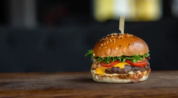 Apetyczny hamburger z sezamem na drewnianym blacie.