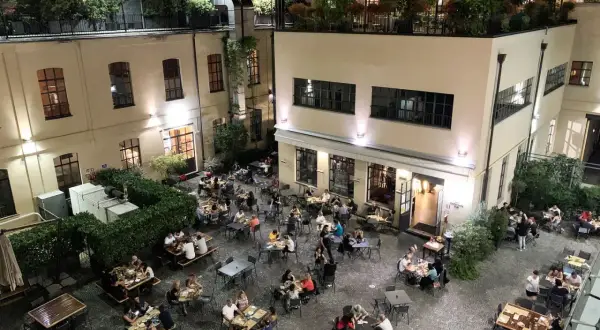 Serata vivace al birrificio La Piazza, con tavoli all'aperto pieni di gente che gode della buona compagnia e delle birre artigianali.