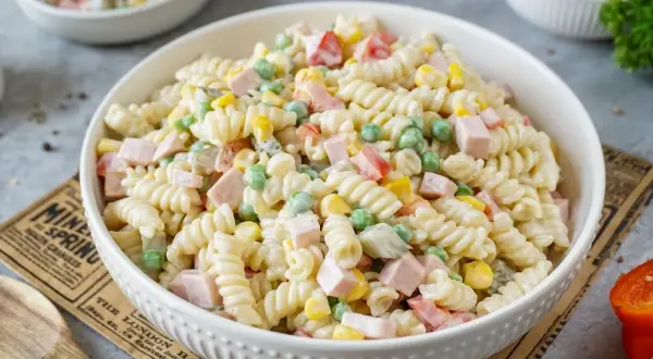 Ein cremiger nudelsalat mit mayonaise, Erbsen, Mais und Schinkenwürfeln. Perfekt für ein Picknick.