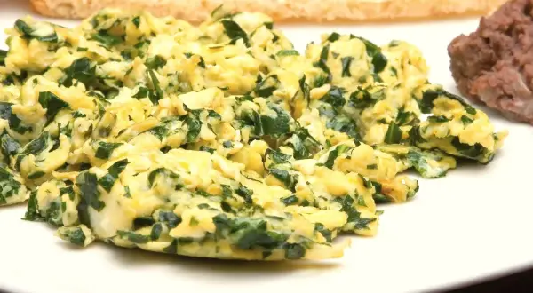 Puszysta jajecznica ze szpinakiem, podana z tostami i fasolką. Pyszne śniadanie.