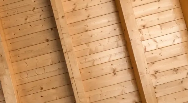 Holzdeckenpaneele mit sichtbaren Balken, bereit zum Streichen. Natürliche Holzmaserung.