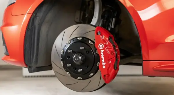 Gros plan sur un étrier de frein Brembo rouge vif sur une voiture de sport. Le disque de frein rainuré est visible. Idéal pour connaître le tarif changement étrier de frein.