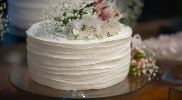 Biały tort udekorowany delikatnymi, żywymi kwiatami i gipsówką. Idealne, jakie żywe kwiaty na tort na specjalną okazję.