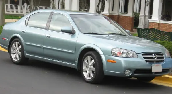 Jasnoniebieski Nissan Maxima 3.5 Turbo stoi przed domem z werandą.