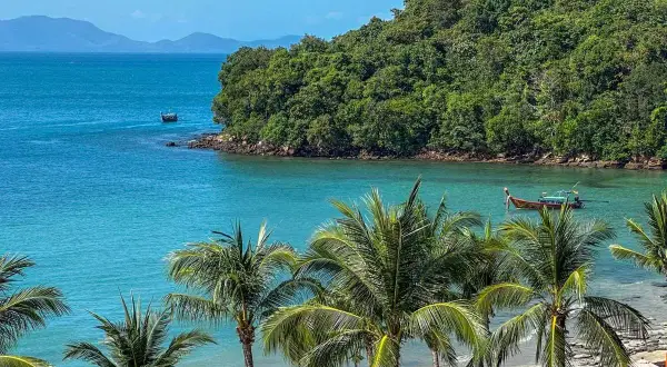 Rajska plaża Ao Nang z palmami, turkusową wodą i łodziami.