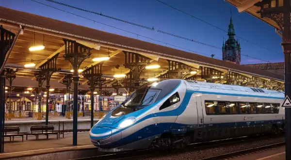Nowoczesny pociąg EIP PKP Intercity na tle zabytkowego dworca w Gdańsku.