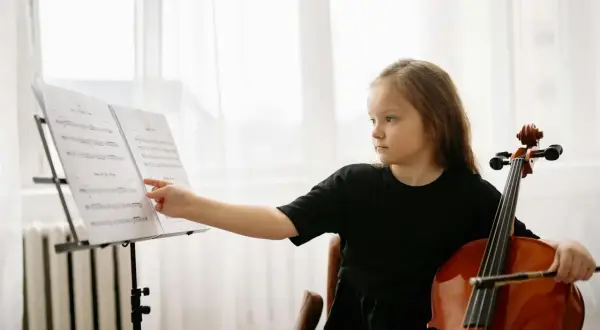 Dziewczynka z wiolonczelą przy nutach. Nauka gry na wiolonczeli to jej pasja.
