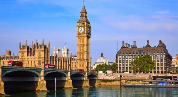 Big Ben Londyn z czerwonymi autobusami na moście i rzeką w tle.