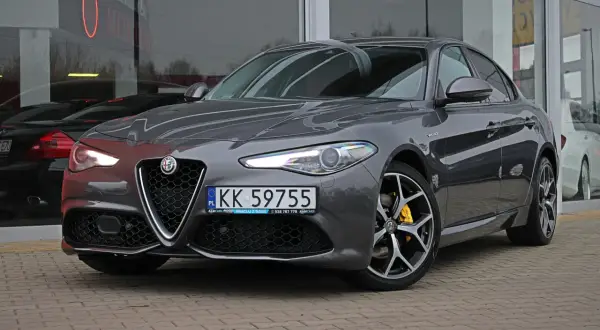 Szary Alfa Romeo Giulia Q4 z żółtymi zaciskami hamulcowymi i felgami z polerowanego aluminium.