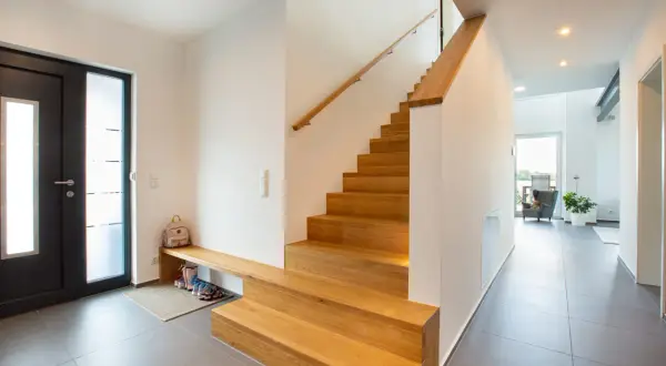 Moderne Ideen für den Hauseingang: Eine Holztreppe mit integrierter Sitzbank und Schuhablage lädt zum Eintreten ein.
