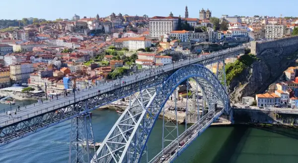 Most Ponte Dom Luís I w Porto, z widokiem na rzekę Douro i kolorowe budynki.