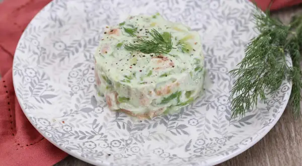 Délicieux tartare de saumon avocat, garni d'aneth frais et servi sur une assiette ornée.