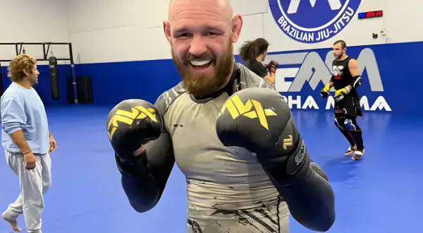 Viacheslav Borshchev ler glatt med boxningshandskar på en MMA-matta.
