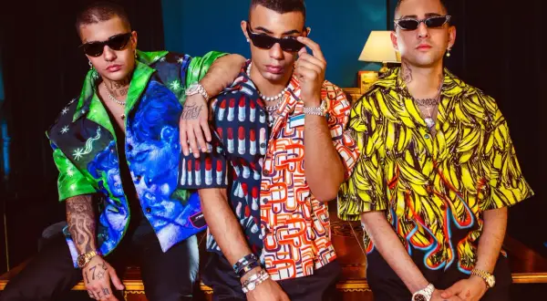 Tre ragazzi con camicie colorate e occhiali da sole, un'immagine che evoca lo stile della dark polo gang.