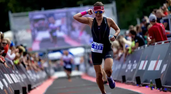 Kobieta w stroju sportowym biegnie, numer startowy 633. To jej trening na 10 km, a tłum kibicuje jej z boku.