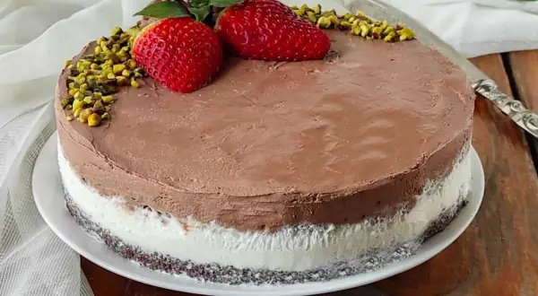 Deliziosa torta al gelato al cioccolato e panna, decorata con fragole, pistacchi e menta.