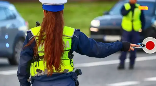 Policjantka zatrzymuje ruch, by uniknąć mandatu 24 punkty karne. Inny funkcjonariusz kieruje ruchem.