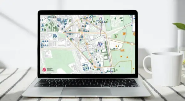 Mapa na ekranie laptopa pokazuje obszar wpisany do rejestru zabytków, z zaznaczonymi budynkami i ulicami.